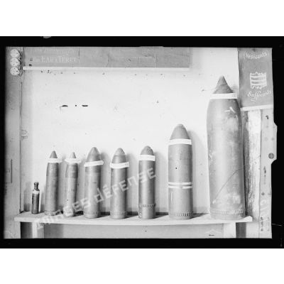Lure, Haute Saône. Centre respiratoire d'armée. Types d'obus à gaz allemands. De gauche à droite, la petite bouteille d'ypérite, telle qu'elle se trouve dans un obus de 77, obus de 77 à l'ypérite, obus de 77 ''?'', obus de 105 à l'ypérite, obus de 105 suffocant, obus de 105 suffocant, obus de 150 suffocant, obus de 210 à l'ypérite. [légende d'origine]