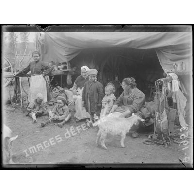 [Photographie d'une famille de réfugiés devant leur campement, en pleine campagne.]