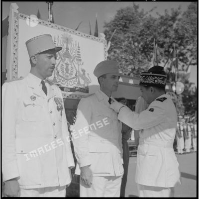 Le roi du Cambodge Norodom Sihanouk décore un militaire français au cours d'une cérémonie commémorant l'anniversaire de la rétrocession de Battambang par le Siam.