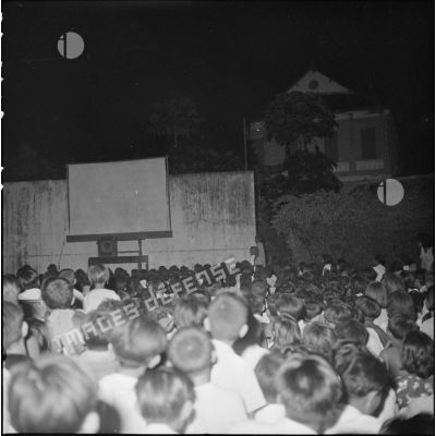 Projection d'un film en plein air le soir sur une place au Cambodge