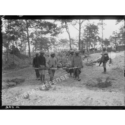 Brancardiers transportant un blessé sur des troncs d'arbre dans le bois de Trou-Bricot. [légende d'origine]