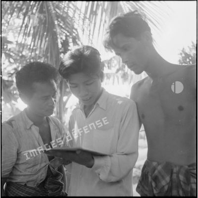 Lecture d'un document distribué par l'armée française au cours d'une tournée de propagande dans la région de Kampot.