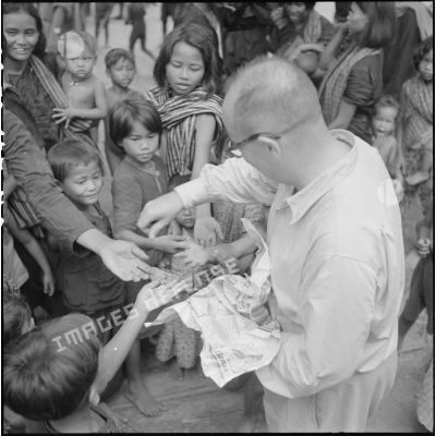 Distribution de bonbons aux enfants au cours d'une tournée de propagande parmi les populations cambodgiennes regroupées dans la province de Kampot
