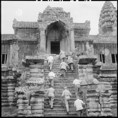 Un groupe d'officiels français monte les marches d'une des tours d'Angkor Vat.