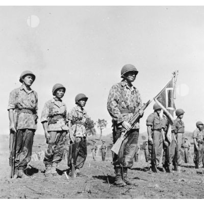 Lors d'une prise d'armes à Na San, le chef de bataillon Bonnigal, commandant le 3e bataillon de parachutistes coloniaux (3e BPC) porte le fanion de son unité.