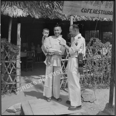 Un restaurateur chinois pose devant son café restaurant aves ses enfants, en compagnie d'un sergent-chef muni d'un appareil photographique Rolleiflex.