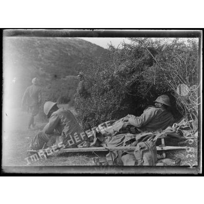 Ravin de Valadja (Macédoine). Poste de secours, un blessé couché sur un brancard et un fiévreux assis. [légende d'origine]