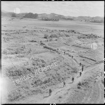 Progression d'une colonne de parachutistes vers Lang Son dans un paysage de rizières et de champs au cours de l'opération Hirondelle.