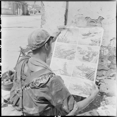 Un parachutiste du 8e groupement de commandos parachutistes (GCP) regarde une affiche de propagande chinoise lors de l'occupation de Lang Son.
