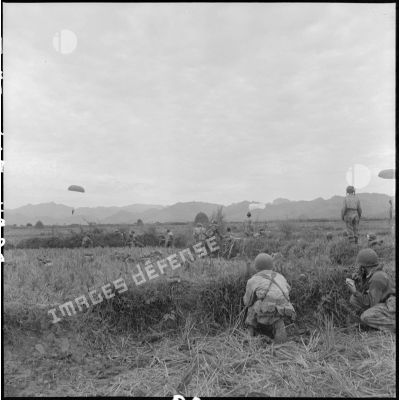 Les premiers parachutistes arrivés au sol protègent leurs camarades pendant leur descente en parachute au cours de l'opération Castor..
