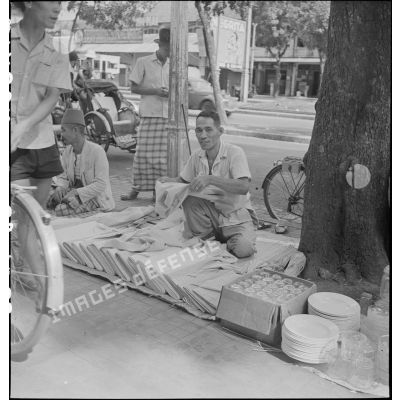 Un marchand de tissus dans les rues de Saigon.