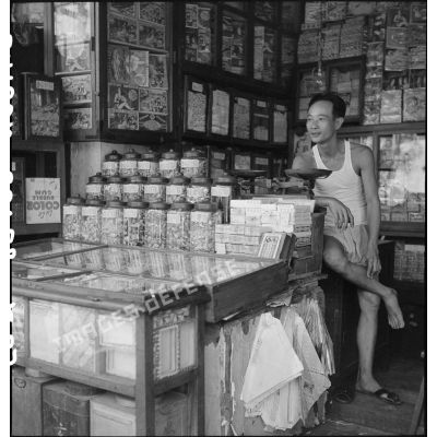 Portrait d'un commerçant dans une échoppe de confiseries à Saigon.