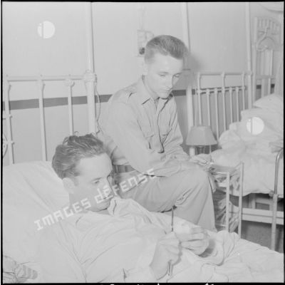 Le cameraman André Lebon, blessé à Diên Biên Phu, s'entretient avec le photographe Jean Petit pendant sa sonvalescence à l'hôpital Grall de Saigon.