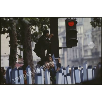 Lors du défilé du 14 juillet 1979 à la Bastille, le public, équipé de périscopes en papier, ou perché sur le poteau d'un feu de circulation pour mieux voir.