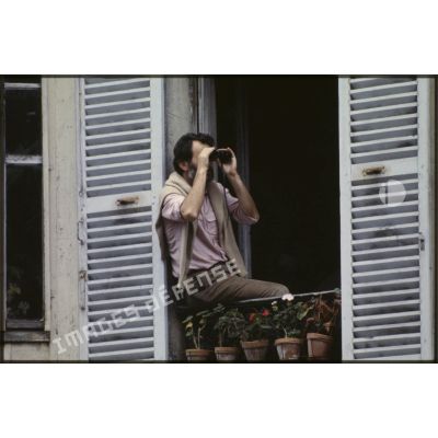 Lors du défilé du 14 juillet 1979 à la Bastille, un curieux équipé de jumelles profite de son balcon pour observer l'événement.<br>