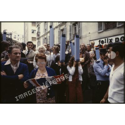 Lors du défilé du 14 juillet 1979 à la Bastille, le public, équipé de périscopes en papier, ou consultant le programme de l'événement.