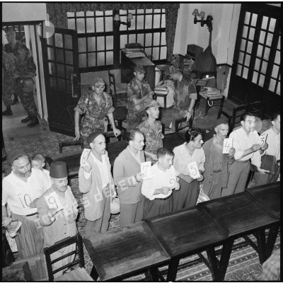 Suspects présentant des numéros pendant une séance d'identification sous le regard des parachutistes du 3e régiment de parachutistes coloniaux (3e RPC).
