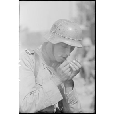 A Catane (Sicile) ou dans la banlieue de la ville, un fantassin du Panzergrenadier-Regiment Hermann Goering allume une pipe.