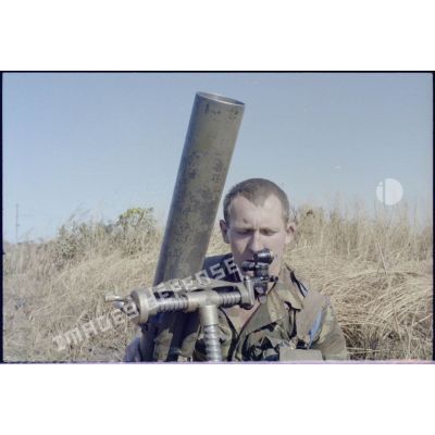 Portrait d'un légionnaire de la 3e compagnie du 2e régiment étranger parachutiste (2e REP) règlant le tir de son mortier de 81 mm. [Description en cours]