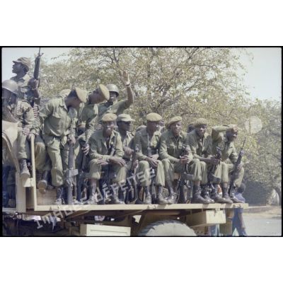 Groupe de soldats zaïrois assis dans un camion, armés de fusils M-16. [Description en cours]