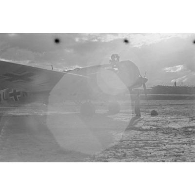 Un orage se rapproche du terrain d'aviation d'Héraklion, des mécaniciens fixent des protections sur les moteurs d'un bombardier Heinkel He-111.