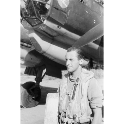Un membre d'équipage de bimoteur Junkers Ju-88 du Aufklärungsgruppe 123 dont l'insigne est reproduit sur le nez de l'appareil.