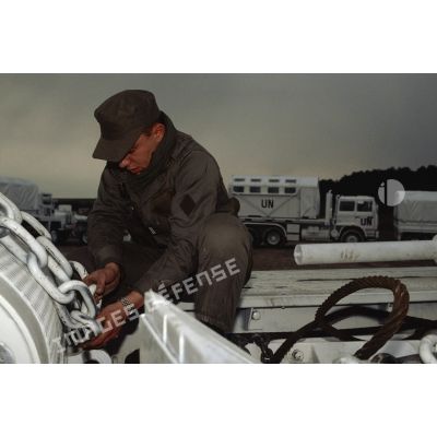 Soldat du 2e régiment d'infanterie de marine (RIMa) fixant un élément mobile avec des chaînes sur un véhicule de l'avant blindé (VAB) aux couleurs de l'ONU.