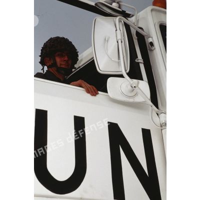 Gros plan sur un soldat derrière la portière siglée UN (ONU) d'un camion Renault TBH 350.