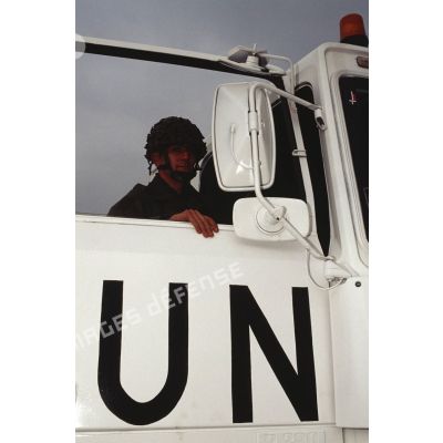 Gros plan sur un soldat derrière la portière siglée UN (ONU) d'un camion Renault TBH 350.