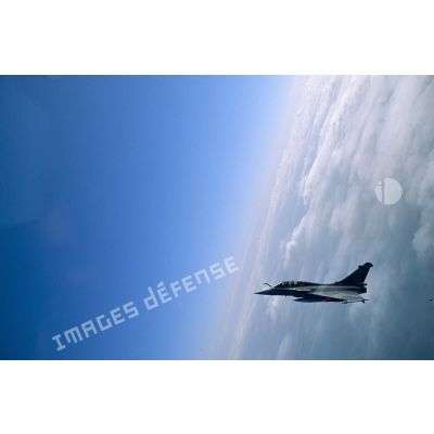 Un avion de chasse Rafale en exercice au-dessus de la Camargue. L’aéronef est en peinture de camouflage et porte des missiles de type MICA.