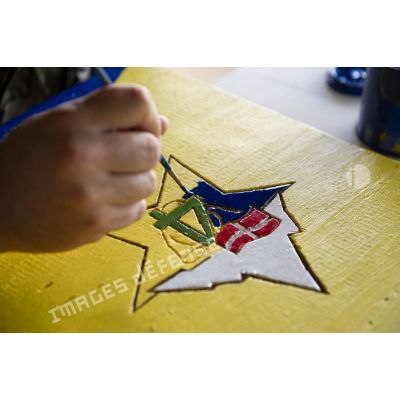 Un soldat du 13e bataillon de chasseurs alpins (13e BCA) peint l'insigne de son unité pour la confection d'un poteau kilométrique à Maripasoula, en Guyane française.