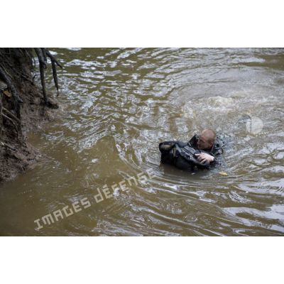 Un stagiaire apprend à traverser une crique avec sac et armement sur la zone d'instruction de Tuff, en Guyane française.