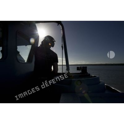 Un membre d'équipage surveille la manoeuvre d'appareillage du navire à tribord de la passerelle de La Gracieuse, en Guyane française.