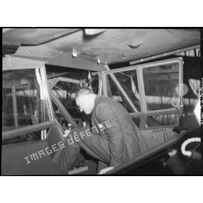 Charles Tillon prend place dans un avion stationné dans un atelier de l'usine Puteaux.