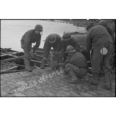 Des sapeurs du génie s'affairent autour d'un moteur hors-bord équipant les bateaux d'assaut pour le franchissement du Rhin.