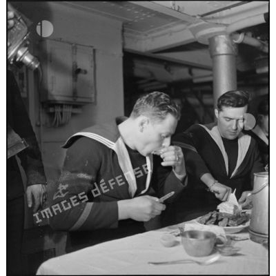 Des marins mangent des huîtres au cours du réveillon de Noël à bord du porte-avions Béarn.