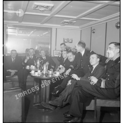 Des journalistes britanniques, en visite à bord du cuirassé Dunkerque, sont reçus dans le carré des officiers supérieurs.