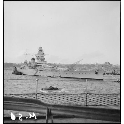 Vue de trois quarts tribord avant du croiseur Dunkerque remorqué dans le port de Brest.