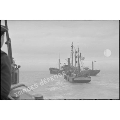Le chalutier Gloria in Excelsis Deo, réquisitionné par la Marine nationale et affecté à la police de la navigation, s'apprête à arraisonner un cargo.