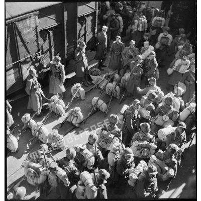 Des soldats d'unités de l'armée d'Afrique, débarqués sur un quai dans le port de Marseille, attendent leur embarquement à bord de wagons ferroviaires.