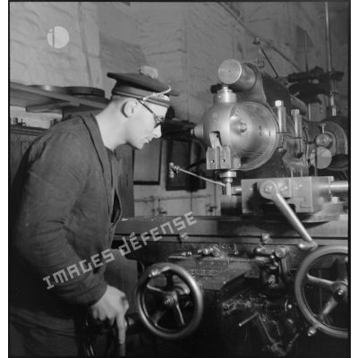 Atelier central de la flotte : un marin travaille une pièce de métal à la fraiseuse.
