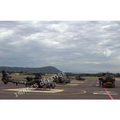 Un camion-citerne effectue le plein de trois hélicoptères Gazelle. Les appareils sont codés AXD et le AXH et BLF.